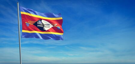 The National flag of Eswatini blowing in the wind in front of a clear blue skyの写真素材