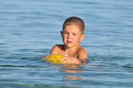 boy in the water playing with a ballの写真素材