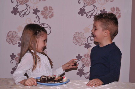A couple of kids enjoy a chocolate cakeの写真素材