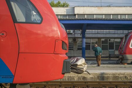 Lonely man waiting for train holding head on railway station