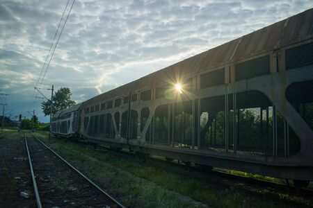 Sunset in the train yard field through old abandoned wagon