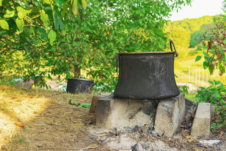Old copper pot for cooking standing on concrete bricks on top of fireplace in the backyardの写真素材