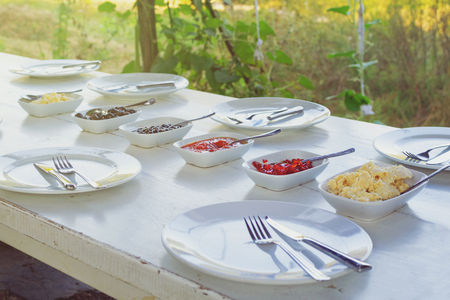 Outdoor white vintage table set for breakfast with empty plates ready for eatingの写真素材
