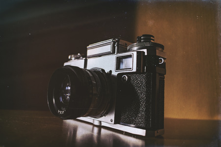 Old style retro analog film camera standing on the shelve with sun shining from the side