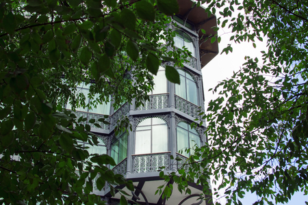 Beautiful old building with balcony and lot of windows on the corner of the street in Tbilisi old town, green foliage colors, Georgiaの写真素材
