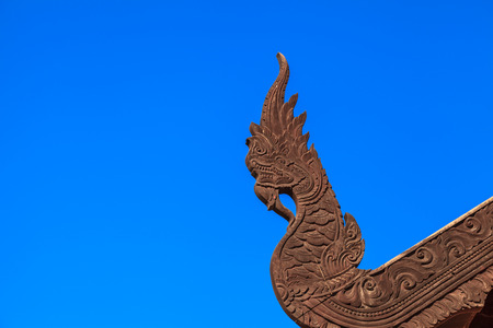 serpent king or king of naga wood carving craft  in thai temple on blue sky backgroundの写真素材
