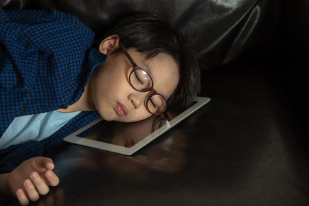 the boy tired form playing game and sleeping on tabletの写真素材