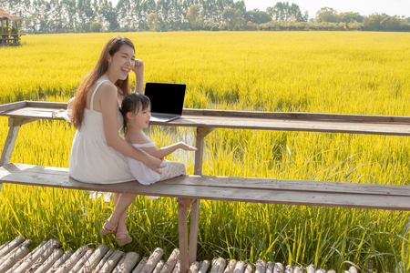 asian working mom and daughter using laptop, urban family on weekendの写真素材