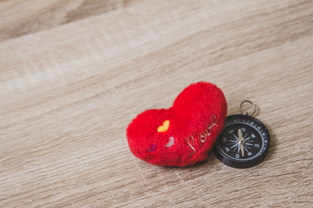 A red heart ball and compass on wooden table with copy space, valentine dayの写真素材
