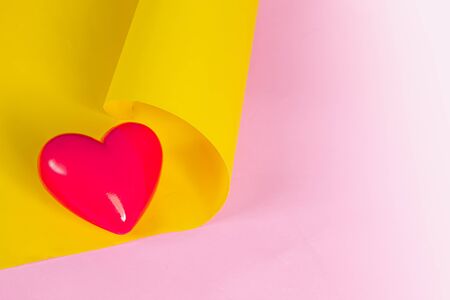 Red heart and roll of  yellow paper with pink background.の写真素材
