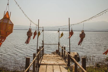 Small wooden bridge with colorful Flag at Kwan Phayao lake, Thailand.の写真素材