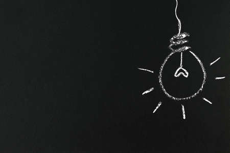 Illustration of Mini heart inside glowing light bulb on blackboard.idea and education concept.