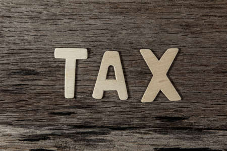 The word TAX is make from wood on wooden background.の写真素材