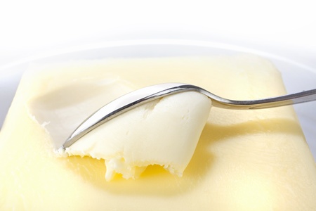 closeup studio shot of block of butter with spoon in it on white plate on white background の写真素材