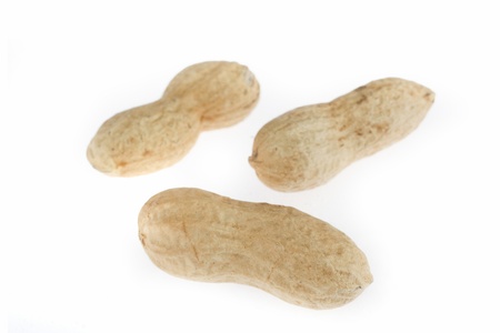  close up shot of three peanuts in their shells on the white background 