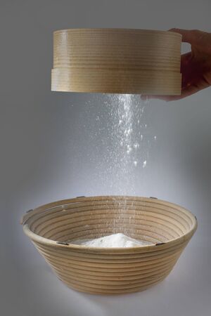 a sieve for flour in action. the cook sows the flour into another container where she will mix...