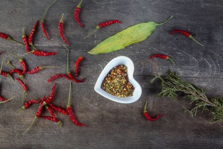 studio shot of assorted spices with whole red peppers rosemary and allium ursinum with melted...