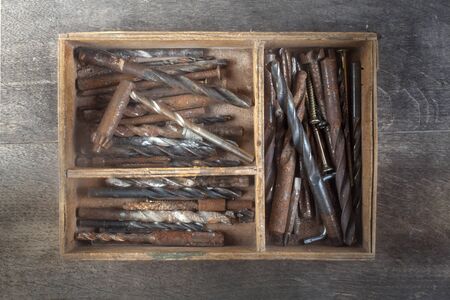 studio photo of wooden box of used drills on wooden background