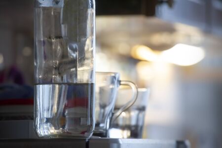 Bottle in Focus and Glass of Water Blurred on a Edge of Fridgeの写真素材