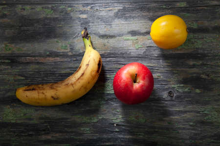 Still Life of Banana, Lemon and Apple on Decayed Wooden Backgroundの写真素材