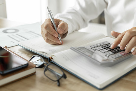 Business man calculating business investment, man in white shirt working on desk in office.の写真素材