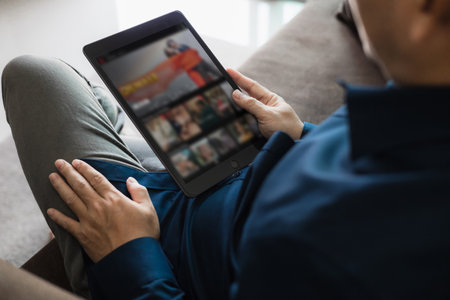 Dressed man watching video on tablet sitting on sofa in houseの写真素材