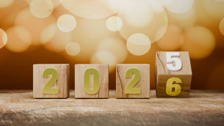 Golden Bokeh Background Illuminates the Wooden Cubes Displaying the Transition from 2025 to a Bright New Year 2026.の写真素材