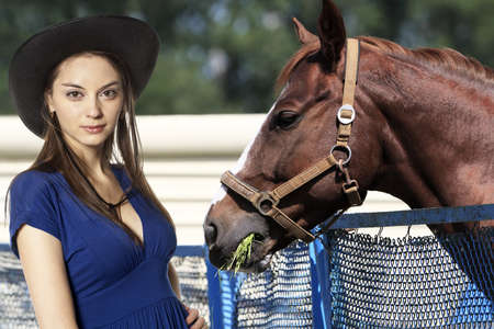 Cowgirl feeding grass her horse の写真素材