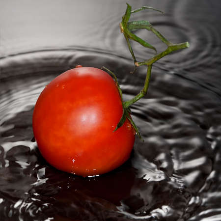 Tomato falled with ripple in water surfaceの写真素材