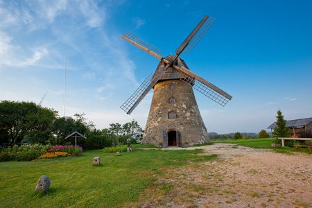 Traditional Old dutch windmill in Latvia against blue sky with white cloudsの写真素材