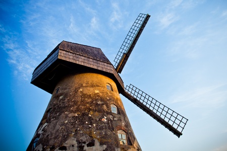 Traditional Old dutch windmill in Latvia against blue sky with white clouds