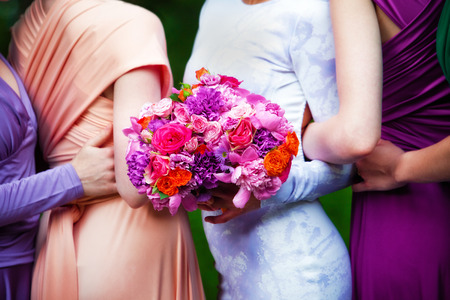 Bridesmaids in colorful dresses with bouquets of flowersの写真素材