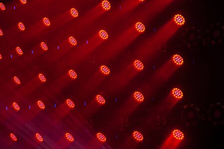 Stage lights of different colors, background of glowing red spotlights