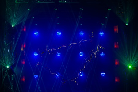 Stage lights of different colors, background of glowing blue spotlights
