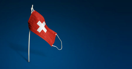Switzerland mask on dark blue background. Waving flag of Switzerland painted on medical mask on pole. Virus Attack flag. Concept of The banner of the fight against the epidemicの写真素材