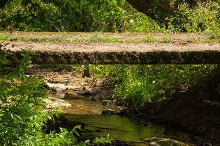 Rural small concrete bridge over small shallow stream and rocky landscape in mountain. Abandoned...