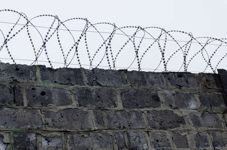 Gloomy gray fence of the prison with barbed wire. Consistency in the conclusion. The concept of individual rights and freedomsの写真素材