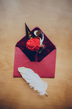 envelope invitation budonier wedding rings on the table in hotel decorated with feathers in claret colorの写真素材