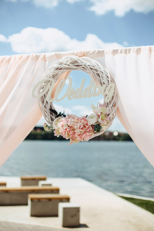 Wedding ceremony on the shore of a lake on a sunny day in pink tones decorated with flowersの写真素材