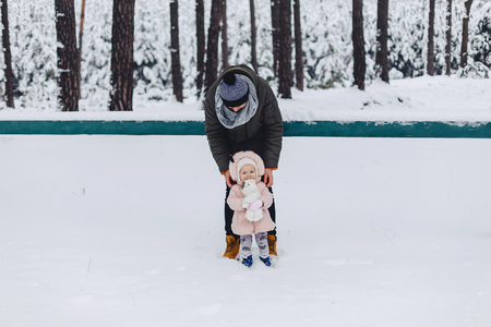 Tattoo and daughter walking with snow-covered pine forest against the background of winter landscapesの写真素材