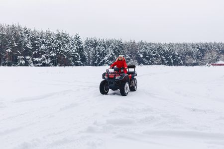 A pretty girl riding a quadrocycle in a picturesque snowy are at the countrysideの写真素材