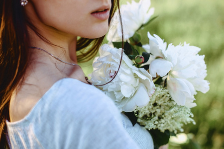 The girl walks with flowers in a field in a bicycle in the back of warm, sunny lightの写真素材