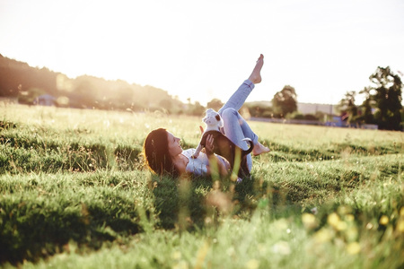 The girl walks with a puppy in a field in a bicycle in the back of warm, sunny lightの写真素材