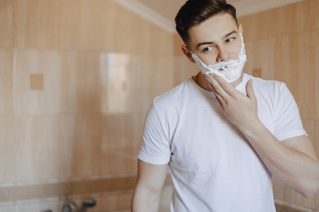morning hygiene, man shaves with foam in the bright bathroomの写真素材
