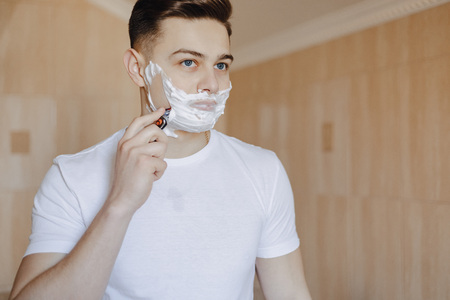 morning hygiene, man shaves with foam in the bright bathroomの写真素材