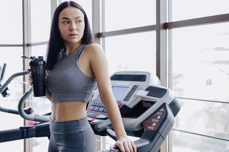 Girl in the gym are trained on treadmill and drink water, smiling and healthy