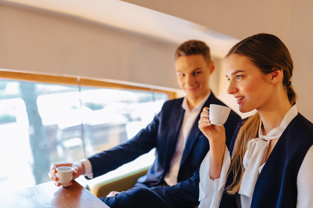A stylish couple drinks morning coffee at the cafe with cozy interior, young businessmen and freelancersの写真素材