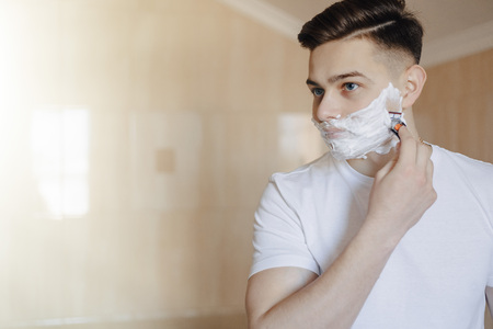 morning hygiene, man shaves with foam in the bright bathroomの写真素材