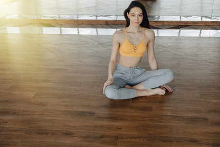 young attractive girl on a wooden floor doing yoga, stretching and relaxing with mirror on backgroundの写真素材