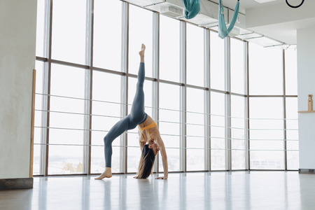 cozy young attractive girl doing fitness exercises with yoga on the floor against the background of...
